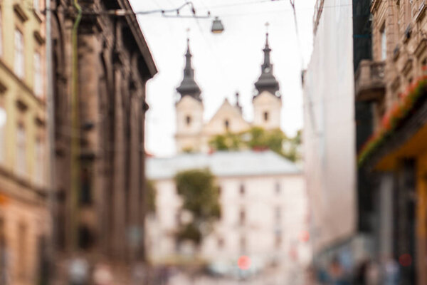 Natural bokeh of old city view, blurred out of focus background. Abstract beautiful backdrop for text or advertising. Unfocused cafes, buildings and people