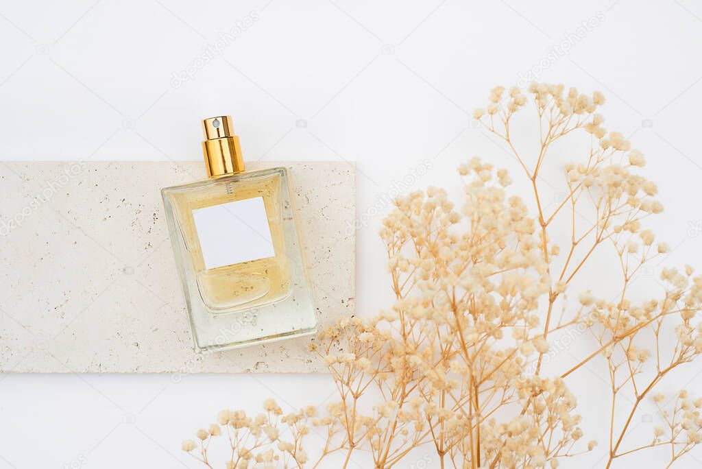 Transparent bottle of perfume on stone plate on a white background. Fragrance presentation with daylight.