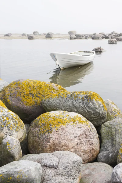 White boat behind large stones Stock Image