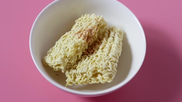 Καρυκεύματα κόκκινο πιπέρι χύνει σε στιγμιαία noodles σε ροζ φόντο. — Αρχείο Βίντεο