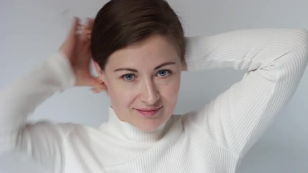 Jeune femme fait coiffure sur un fond blanc, gros plan. — Video
