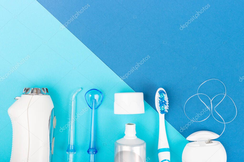 Toothpaste, toothbrush and dental irrigator on a blue background, copy space.