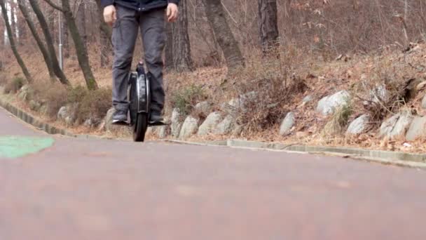 한 남자가 도시 공원에서 전기 외발자전거를 타고 정면을 바라본다 — 비디오