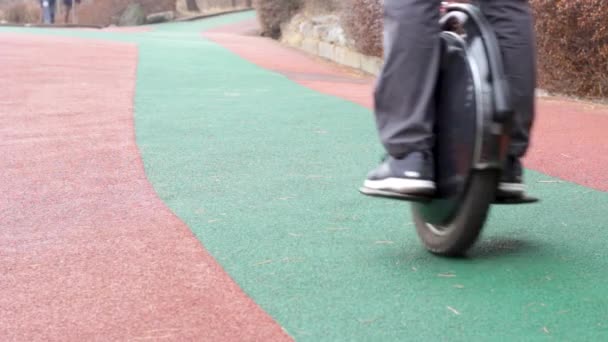 En man rider en elektrisk enhjuling i stadsparken, utsikt framifrån — Stockvideo