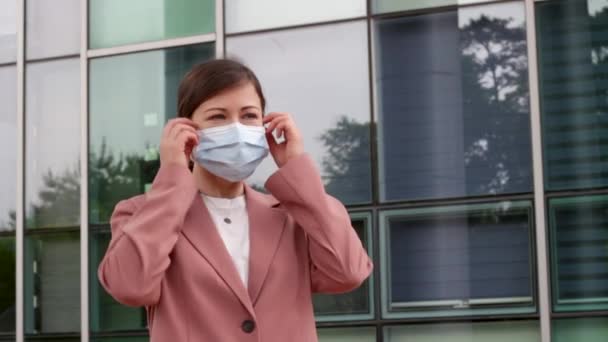 Frau zieht weiße Arztmaske vor Bürogebäude ab. — Stockvideo