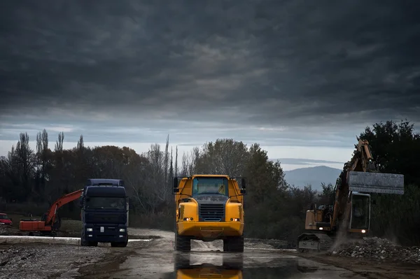 Строительная площадка с грузовыми автомобилями и экскаватором — стоковое фото