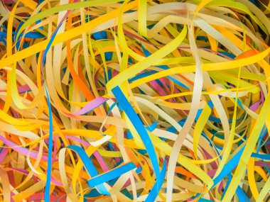 Abstract background close up colorful holiday paper ribbons.Celebration serpentine.Bunch of orange,blue,pink,yellow curly mixed tapes,streamers.Concept of congratulation,festive event,fun.Copy space