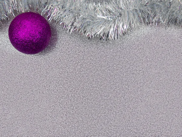 Top view one dark purple Christmas tree ball,in corner,white tinsel upper border,shiny shimmering silver background.Christmas,New Year,birthday holiday decoration.Horizontal banner,copy space,pattern.