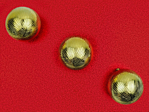Top view close up 3 three golden Christmas tree sparkling ball diagonally across shimmering red sequined background.Christmas, New Year, birthday holiday decor.Horizontal banner design, copy space.