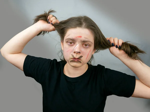 Portrait teenage girl holding hair with her hands,aggressively painted face.Protest action,adolescent self-determination,imposed stereotype rejection,sexual self-identification,conflict with adults.