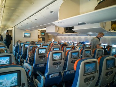 Moskova, Rusya-Haziran 03.2021: Uçak kabini içi, monitör ekranlı yolcu koltuğu. Maskeli insanlar uçağa biniyor, arka planda kamarot duruyor. Seyahat kavramı, seçici odaklanma..