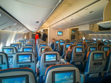 Moskova, Rusya-Haziran 03.2021: Uçak kabini içi, monitör ekranlı yolcu koltuğu. Maskeli insanlar uçağa biniyor. Uçuş görevlisi, uçuş görevlisi, arka planda hostes..