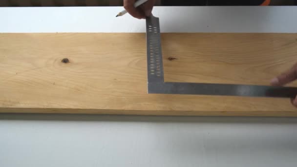 用铅笔和建筑用正方形的锯线 用粉刷过的白色台面 把男性晒黑的木匠的手合拢起来 把木板劈成两半 — 图库视频影像