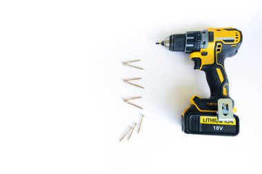 Yakın plan siyah sarı elektrikli kablosuz tornavida yok, yeni değil, kurşun listesinin şablonu olarak serili sarı metal vida sayısı, arka plan olarak beyaz ahşap masa. Boşluğu kopyala.