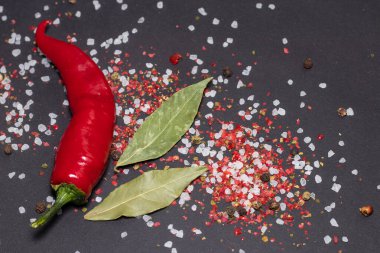 Deniz tuzu ve koyu yapraklı kırmızı biber ve siyah üzerine renkli biber..