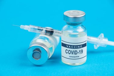 Aşılama. Şırınga ve aşı COVID-19. Mavi arkaplanda Coronavirus.