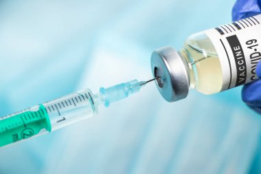 Aşılama. Şırınga ve aşı COVID-19. Mavi arkaplanda Coronavirus.