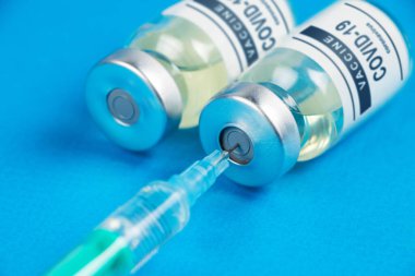 Aşılama. Şırınga ve aşı COVID-19. Mavi arkaplanda Coronavirus.