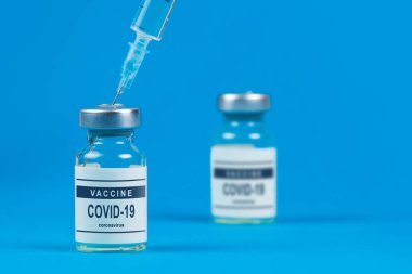 Aşılama. Şırınga ve aşı COVID-19. Mavi arkaplanda Coronavirus.