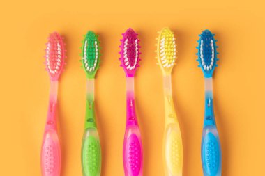 Sarı arkaplanda renkli diş fırçaları.