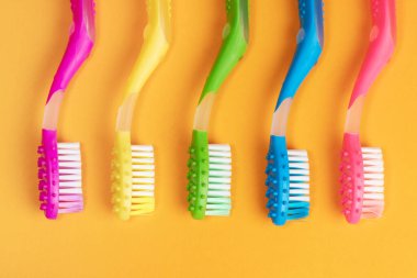 Sarı arkaplanda renkli diş fırçaları.