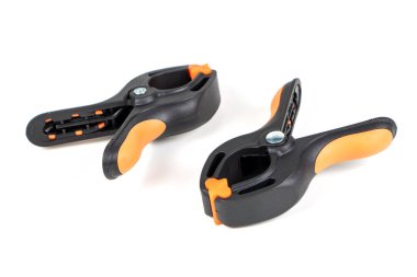 Plastik yay kıskacı beyaz arkaplanda izole edilmiş. Kıskaç ekipmanı. Çalışan el aleti. Siyah ve turuncu yay kıskacı. Yakın çekim..