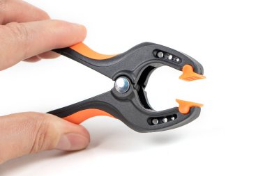 Plastik yay kıskacı beyaz arkaplanda izole edilmiş. Kıskaç ekipmanı. Çalışan el aleti. Siyah ve turuncu yay kıskacı. Yakın çekim..