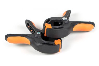 Plastik yay kıskacı beyaz arkaplanda izole edilmiş. Kıskaç ekipmanı. Çalışan el aleti. Siyah ve turuncu yay kıskacı. Yakın çekim..