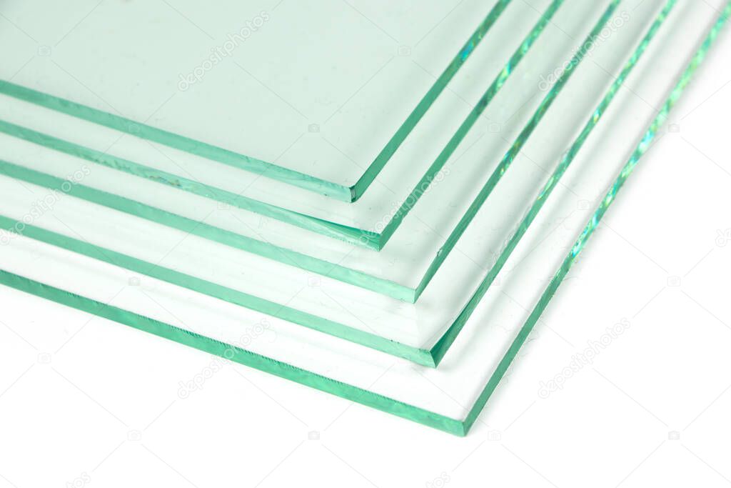Sheets of Factory manufacturing tempered clear float glass panels cut to size. White background.