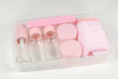 Beyaz bir arka planda şeffaf kozmetik poşet içinde küçük bir şişe setiyle seyahat et..