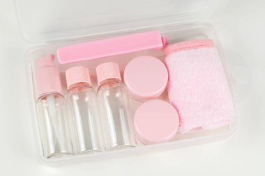 Beyaz bir arka planda şeffaf kozmetik poşet içinde küçük bir şişe setiyle seyahat et..