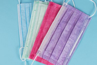 Mavi arka planda farklı renkli tıbbi maskeler..