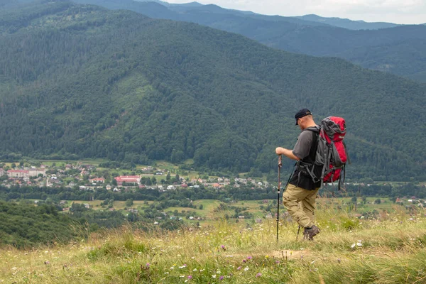Man with camping equipment walks in the mountains.