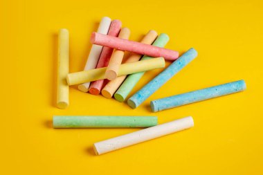 Sarı arkaplanda sıralanmış çeşitli renklerde tebeşirler.