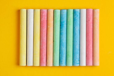 Sarı arkaplanda sıralanmış çeşitli renklerde tebeşirler.