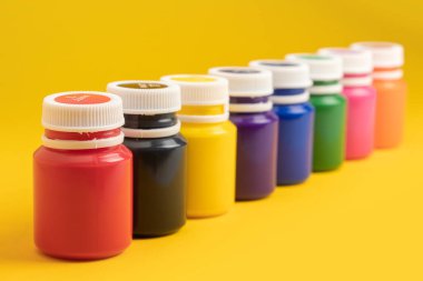 Sarı arka planda boya şişeleri.