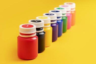 Sarı arka planda boya şişeleri.