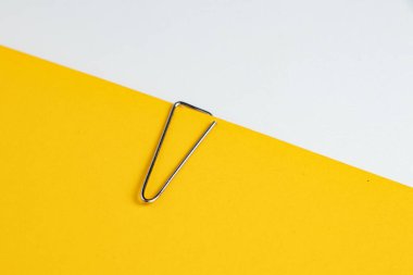 Sarı arkaplanda ataç olan boş beyaz not kağıdı.