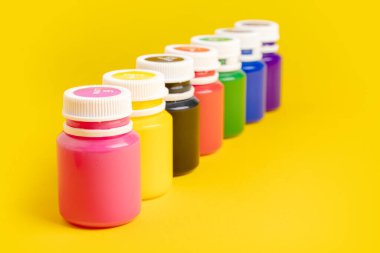 Sarı arka planda boya şişeleri.