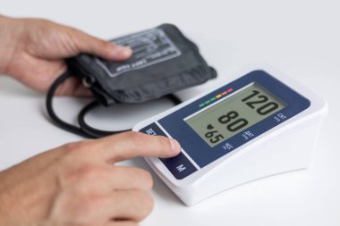 Closeup of unrecognizable male patient using modern tonometer at home. Cropped of middle-eastern man measuring his blood pressure, making self checkup