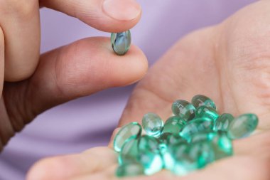 Elinde mavi ilaç kapsülleri tutan ve toplayan bir adam..