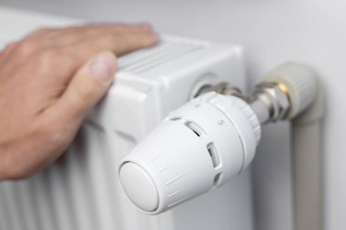 Adam ısıtıcının üstünde ellerini ısıtıyor. İyi bir merkezi ısıtma ihtiyacı kavramı.