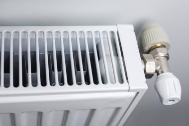 A steel panel heating radiator is placed under the windowsill on a white.