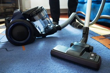 Halıyı elektrikli süpürgeyle temizleyen adam, yakın plan..
