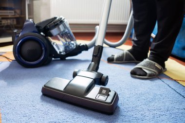 Halıyı elektrikli süpürgeyle temizleyen adam, yakın plan..