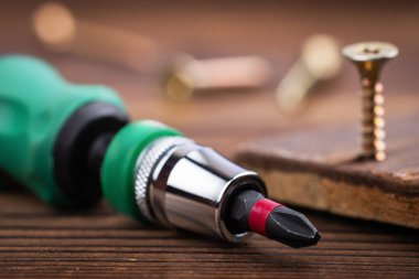 Tornavida ve tahta arka planda vidalar. Kendini beceren vida. Makro fotoğrafı vidalıyor. Yapı soyut. Sanayi geçmişi.