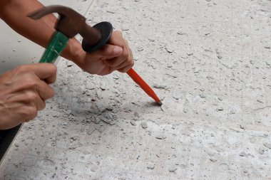 Bir tamirci, alanı yeni fayanslara hazırlamak için keskiyi yere çakıyordu..