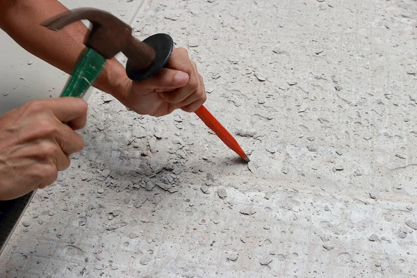Bir tamirci, alanı yeni fayanslara hazırlamak için keskiyi yere çakıyordu..