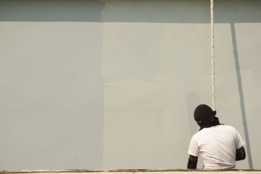 Bir erkek işçi iple yüksek bir binayı boyuyor..