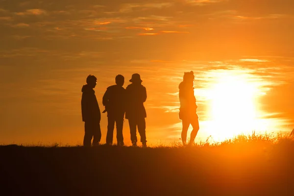 Gezginlerin siluetleri dağlarda gün batımının turuncu ışığına karşı.